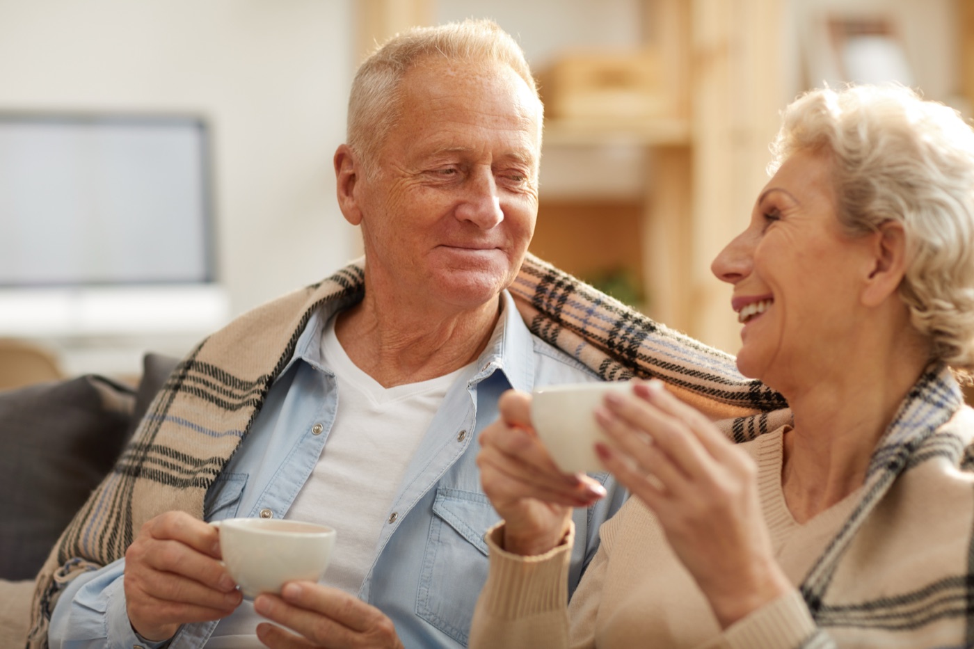 A happy senior couple sharing tea together at home in warm afternoon light
